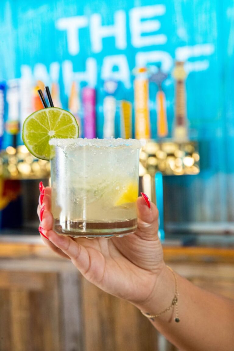 Cocktail with lemon wedge in a salt-rimmed glass garnished with a lime slice