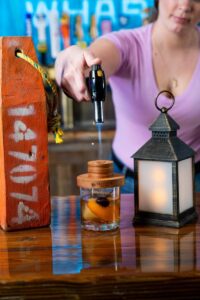 Bartender warming a Heaven’s Door cocktail with a portable bar blowtorch