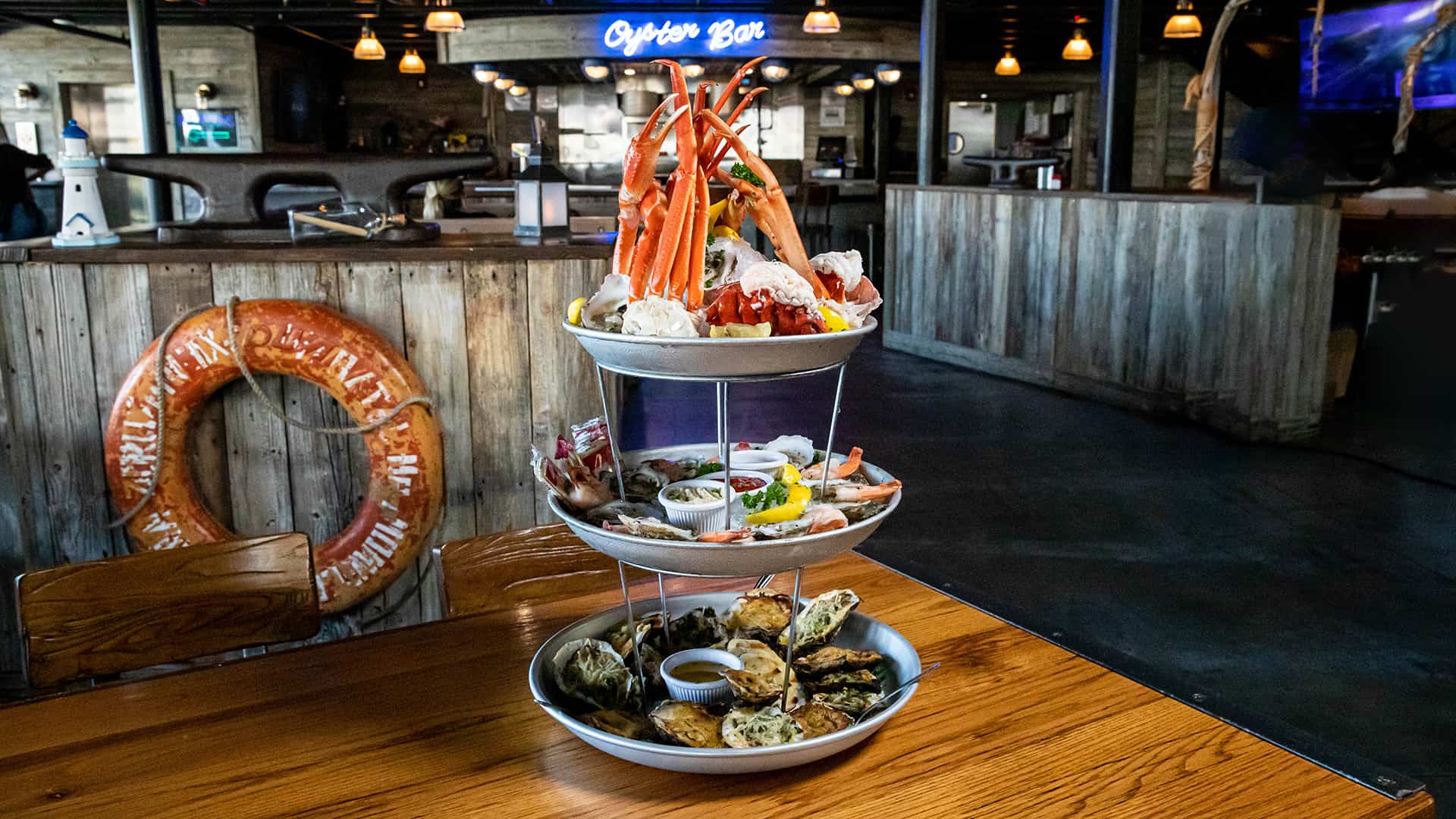 Three-tier seafood tower at The Wharf featuring oysters, crab legs, and scallops