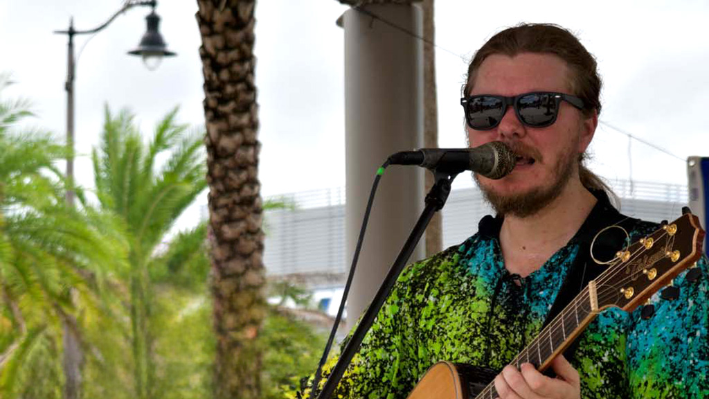Ben Browne singing and playing guitar on the Promenade at Sunset Walk