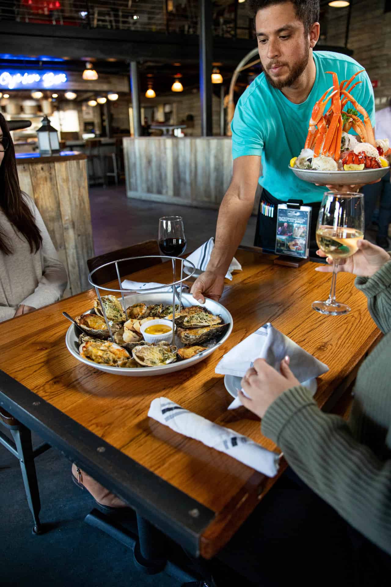 Server at The Wharf setting a plate of oysters on a table