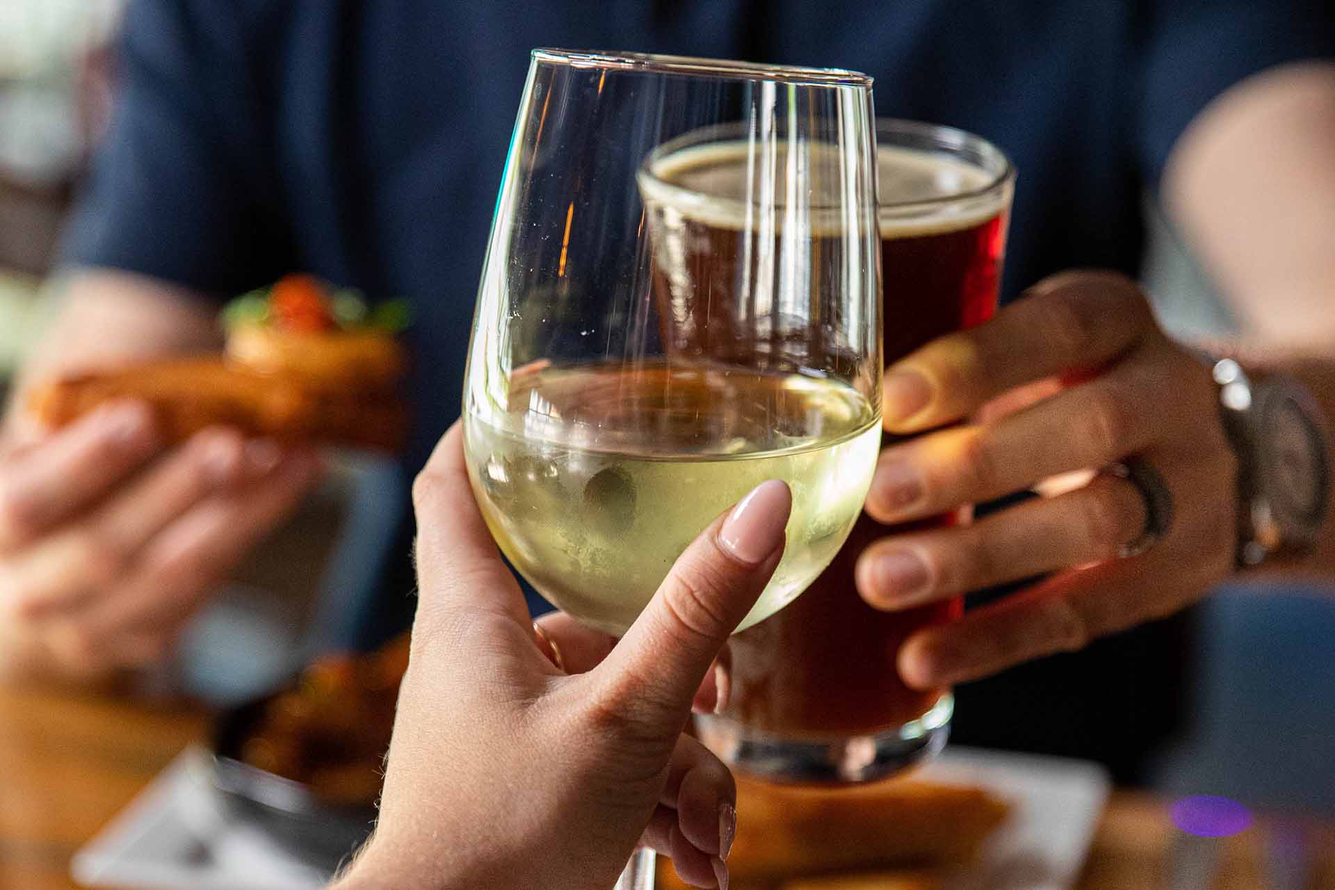 Toasting a glass of white wine with a pint of beer